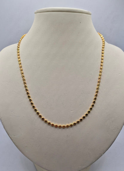 A gold beaded chain necklace displayed on a cream-colored jewelry bust against a light gray background.