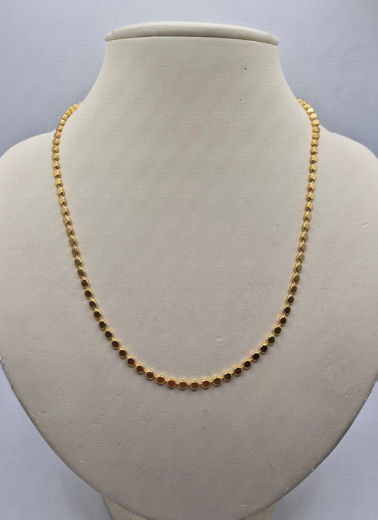A gold beaded chain necklace displayed on a cream-colored jewelry bust against a light gray background.